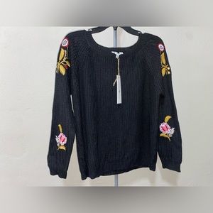 Woman’s black sweater with flowers on sleeves